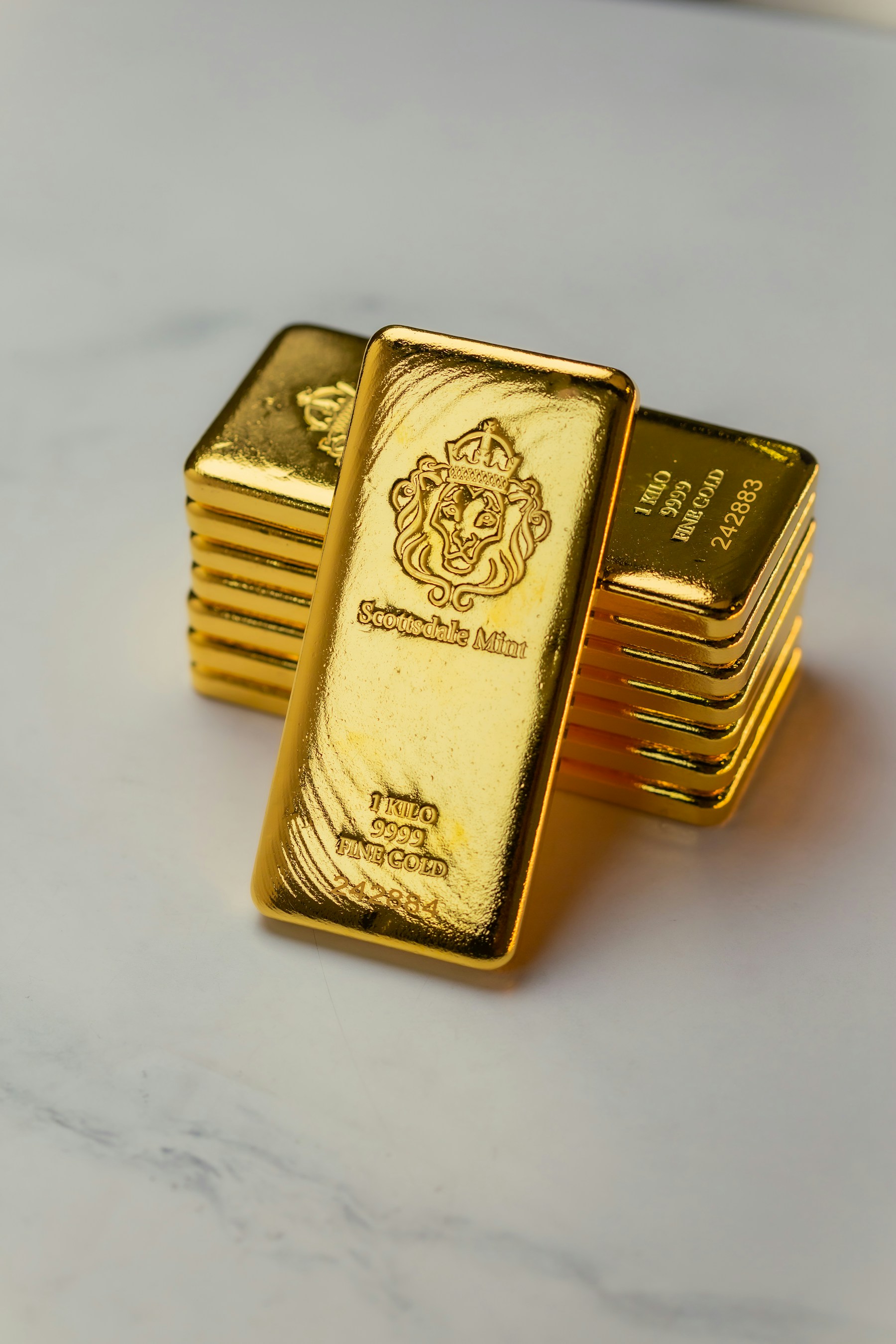 A stack of one-kilogram fine gold bars on white marble