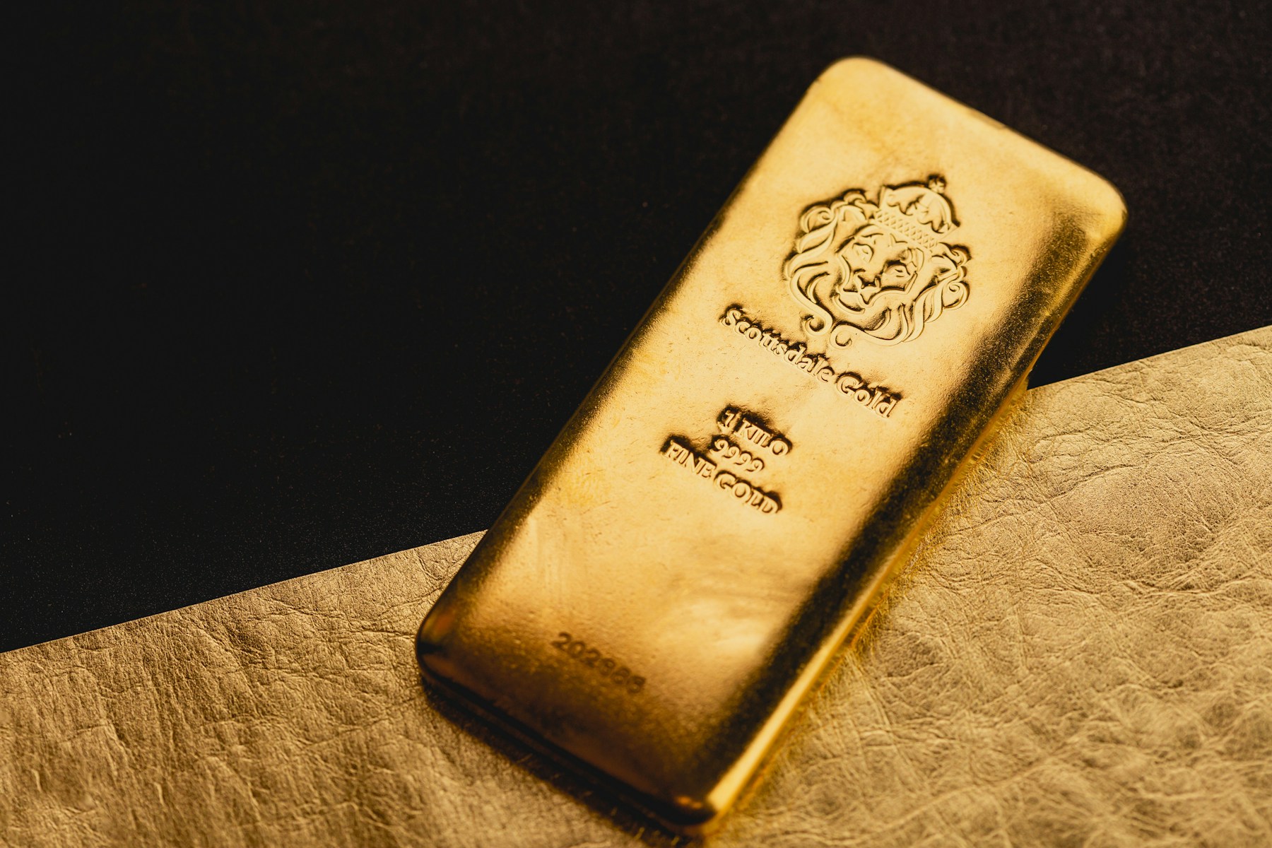 A minted fine gold bar on a gold surface