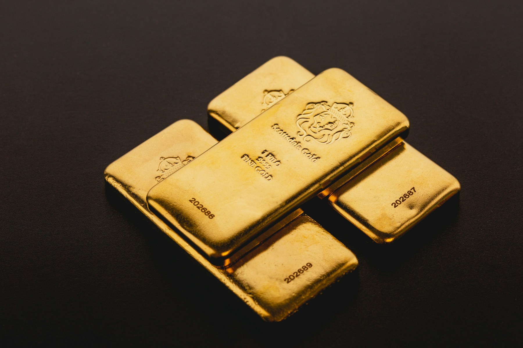 Fine gold investment bars laid on a dark surface