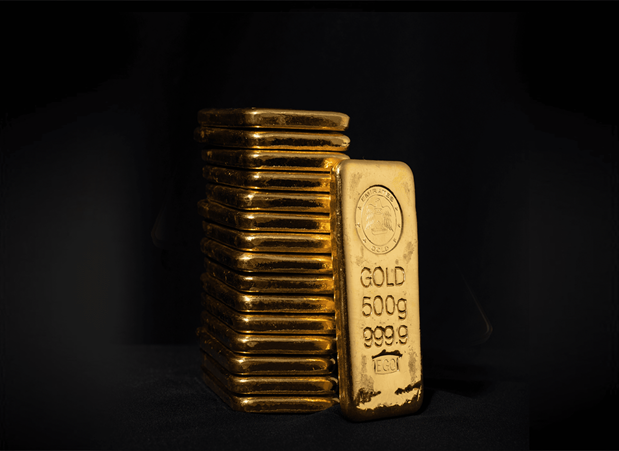 A stack of ten tola gold bars beside a 500 gram bar